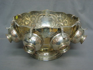 A circular embossed silver plated punch bowl raised on a spreading foot with lion mask ring handles and 6 matching cups