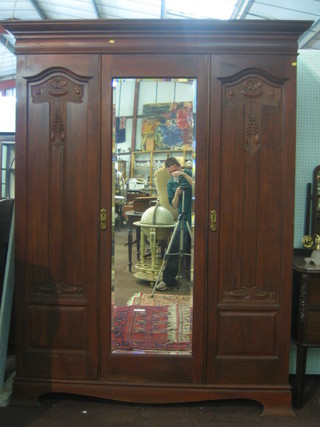 A Maples Edwardian Art Nouveau carved walnut triple wardrobe with moulded cornice, enclosed by a bevelled plate mirror panelled door 66"