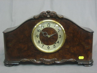 An American Art Deco striking mantel clock with silvered dial and Arabic numerals contained in a walnut arch shaped case