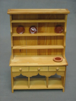 A pine dolls house Welsh dresser with raised back fitted 3 drawers, the base fitted a potboard 5"
