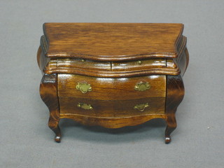 A dolls house mahogany bombe shaped commode fitted 2 short drawers above 2 long drawers, raised on cabriole supports 4"