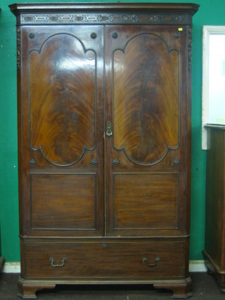 An Edwardian Chippendale style mahogany wardrobe with moulded cornice and blind fret work frieze, enclosed by a pair of arch shaped panelled doors the base fitted a drawer, raised on ogee bracket feet 51"