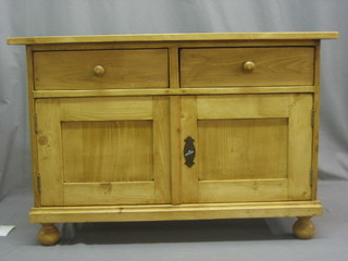 A Continental stripped and polished pine cabinet, the upper section fitted 2 drawers, the base fitted a cupboard enclosed by a panelled door, raised on bun feet 32"