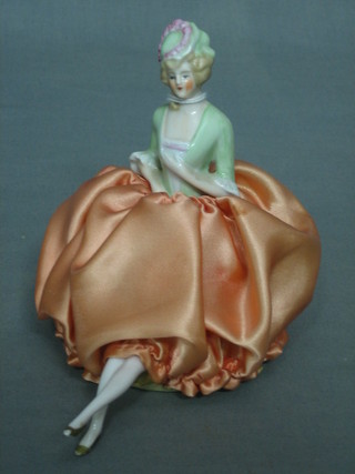 A 1930's porcelain pin cushion in the form of a seated lady