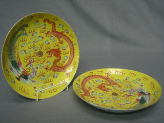 A pair of Oriental circular famille rose yellow glazed bowls decorated dragons, the reverse with 6 character marks 9 1/2"