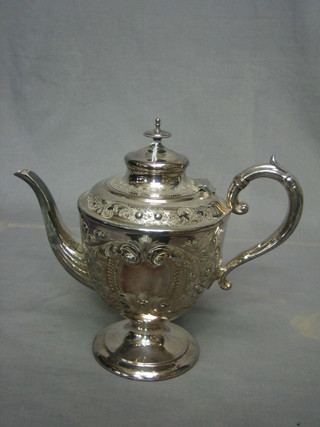 An embossed Britannia metal coffee pot with hinged lid, raised on a circular spreading foot