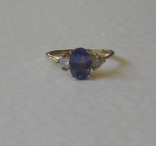 A gold dress ring set a blue stone supported by 2 diamonds