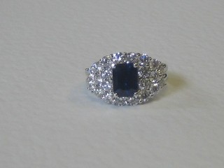 A lady's 18ct white gold dress ring set a rectangular cut sapphire surrounded by numerous diamonds, approx 1.13/0.87ct