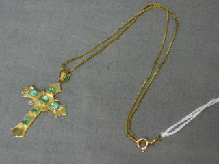A gold cross set emeralds and hung on a fine chain