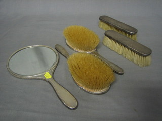 An Art Deco 5 piece silver backed dressing table set comprising hand mirror, pair of hair brushes, pair of clothes brushes with engine turned decoration