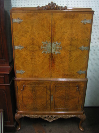A 1950's Queen Anne style figured walnut cocktail cabinet enclosed by panelled doors, raised on cabriole supports 34"