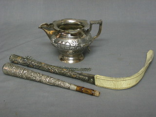 An Eastern embossed "silver" cream jug, a parasol handle and a small whip