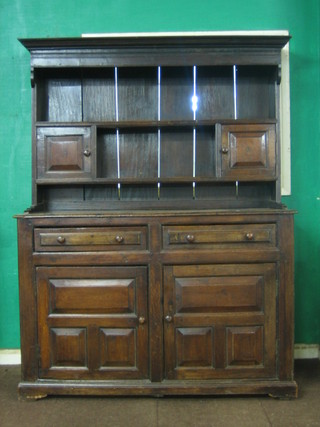 An 18th Century oak dresser with raised back fitted 2 shelves flanked by a pair of cupboards, the base fitted 3 long drawers above a double cupboard enclosed by panelled doors 54"