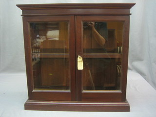 A 19th Century mahogany table top display cabinet the interior fitted a shelf and enclosed by a pair of glazed panelled doors, raised on a platform base 23" 