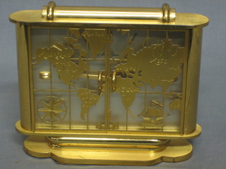 A 1950's 8 day travelling clock with rectangular silvered dial contained in a gilt case enclosed by pierced gilt panelled doors, decorated a map of the world by St Ralise
