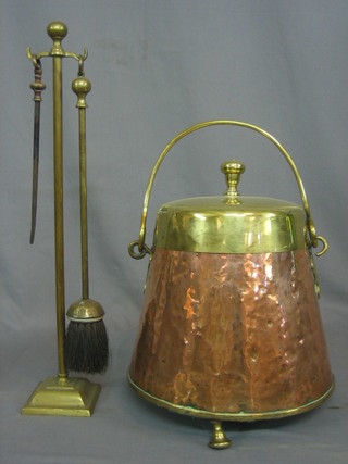 A Dutch copper and brass cylindrical coal bucket with brass swing handle, raised on 3 bracket feet