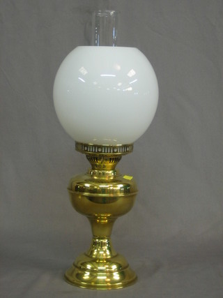 A brass oil lamp with opaque glass chimney and clear glass shade