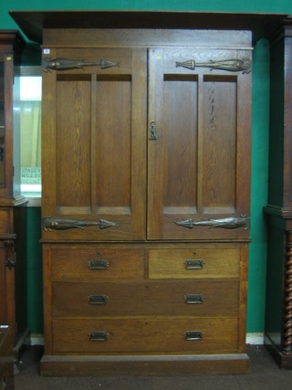 An  Art Nouveau oak linen press with moulded cornice, the upper section with 4 trays enclosed by panelled doors with copper hinges, the base fitted 2 short and 2 long drawers 61"
