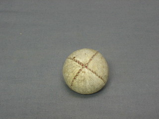 An antique golf ball with red stitching