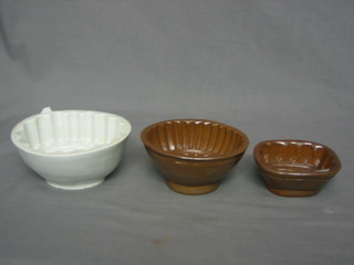 An oval white glazed jelly mould with floral decoration 6", a brown glazed jelly mould with reeded decoration 5", 1 other with sheaths of corn decoration (3)