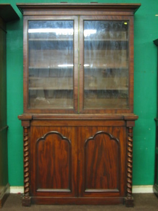 A 19th Century mahogany bookcase on cabinet, the upper section with moulded cornice, the interior fitted adjustable shelves enclosed by glazed panelled doors, the base fitted a secret drawer above a double cupboard enclosed by arched panelled doors, with columns to the sides 50"