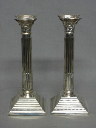 A pair of silver plated column candlesticks with Corinthian capitals and stepped bases 10"