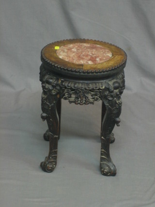 A circular carved Padouk jardiniere stand with pink veined marble top, raised on carved cabriole supports 12"