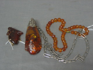An "amber" brooch, an amber coloured pendant hung on a silver chain and an amber coloured brooch