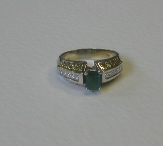 A gold dress ring set an emerald surrounded by diamonds 
