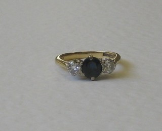 A gold dress ring set a blue coloured stone supported by 2 diamonds