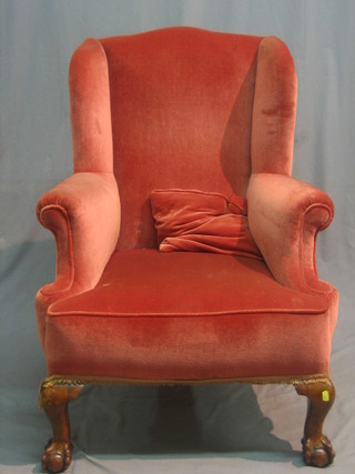 A Georgian style mahogany framed winged armchair upholstered in pink material and raised on cabriole ball and claw supports