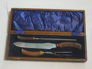 A 3 piece carving set with stag horn handle comprising carving knife, fork and steel, in an oak canteen box