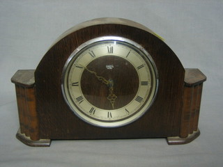 A 1950's Swiss battery operated mantel clock with silvered dial contained in an oak arch shaped case 5-10