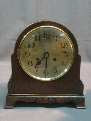 An Art Deco striking mantel clock with silvered dial and Arabic numerals contained in an oak arch shaped case