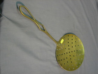 A circular pierced brass cream skimmer