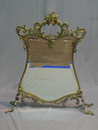 An Art Nouveau pierced brass fire screen incorporating a bevelled plate panel to the centre