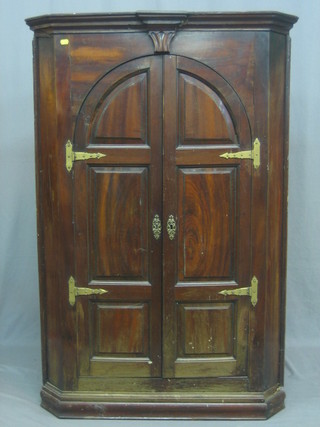 A Georgian mahogany hanging corner cabinet with moulded cornice, the interior fitted shelves enclosed by arch panelled doors 36"
