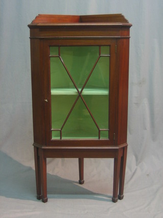 An Edwardian mahogany corner cabinet with raised back, the interior fitted shelves enclosed by an astragal glazed panelled door, raised on square supports ending in spade feet 23"