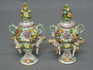 A  pair of Continental miniature porcelain twin handled vases with floral encrusted and cherub decoration 5"