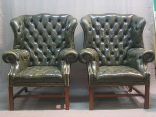 A handsome pair of Georgian style mahogany winged armchairs, upholstered in green buttoned back leather, raised on square supports with H framed stretcher