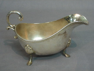 A Georgian style silver plated sauce boat with gadrooned border and C scroll handle, raised on 3 feet