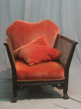 A 1930's beech framed, single cane bergere armchair upholstered in pink material, raised on cabriole supports