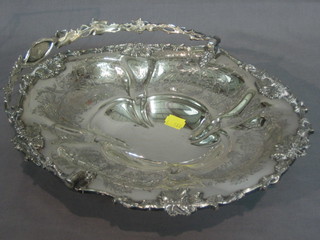 An oval engraved silver plated cake basket with swing handle, raised on an oval spreading foot