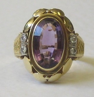 A gold dress ring set an oval cut amethyst and having 4 diamonds to the shoulders