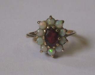 A 9ct gold dress ring set an oval cut garnet surrounded by opals