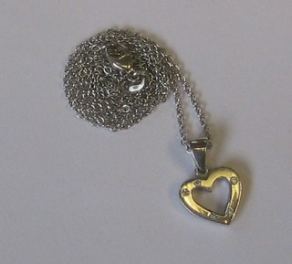 A white gold pendant in the form of a heart set diamonds, hung on a fine gold chain