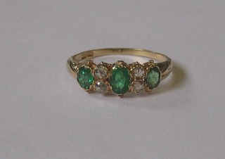 A lady's 18ct yellow gold dress ring set 3 oval cut emeralds and 4 diamonds