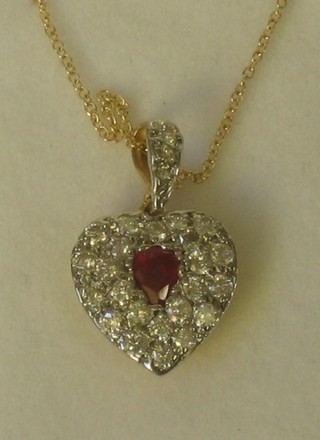 A lady's heart shaped gold pendant set a ruby surrounded by numerous diamonds