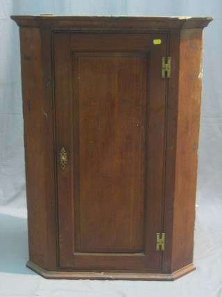 An 18th/19th Century oak corner cabinet with moulded cornice, the interior fitted shelves enclosed by a panelled door, 27"