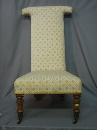 A Victorian walnut framed Pre Dieu chair upholstered in yellow floral material, raised on turned supports with castors